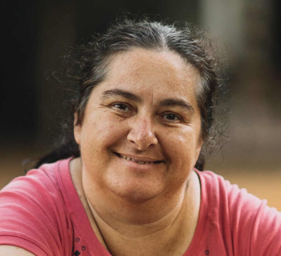 smiling woman with dark hair tied back in a ponytail.