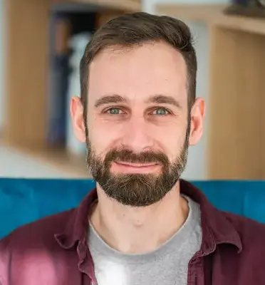 smiling man with a short beard and dark brown hair.